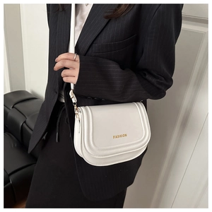 Detail of white leather saddle bag with gold 'FASHION' text on striped suit model