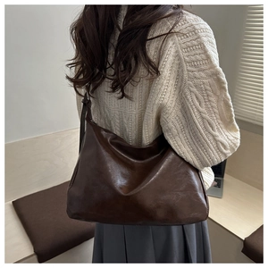 Deep brown leather hobo bag side view on shoulder with a minimalist casual aesthetic