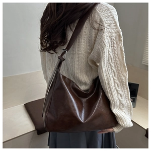 Grand sac à bandoulière marron foncé en cuir synthétique porté par un mannequin