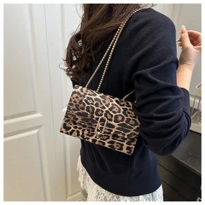 Détail du sac à rabat léopard avec une boucle en U dorée et une bandoulière en chaîne