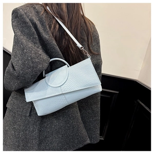 Bolso azul claro con efecto cocodrilo en modelo con bandolera y asa redonda