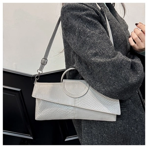 Bolso de mano gris con textura de cocodrilo y cuero liso sobre un abrigo de lana
