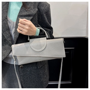 Detalle de bolso gris con textura de cocodrilo y asa plateada elegante