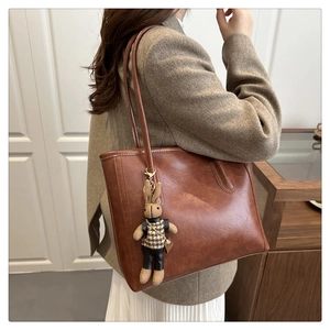 Brown vintage faux leather tote bag detail with stylish knitted rabbit charm on strap