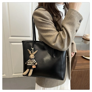 Detail of black leather tote bag featuring a cute bunny pendant for commuter style