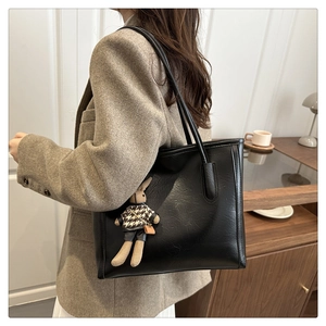 Detail of a large black tote bag with a houndstooth rabbit pendant on a model