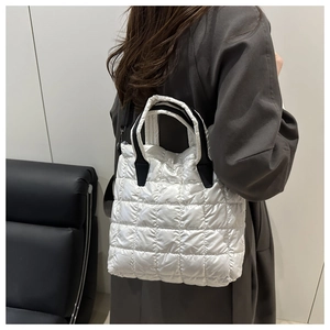 Side view of white quilted tote bag worn as a shoulder bag showing the large capacity size