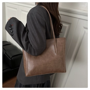 Detail of dark brown leather tote bag with vintage texture shown on a female model
