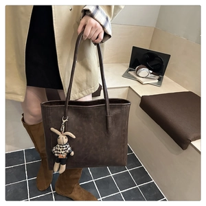 Detailed view of deep brown vintage leather tote bag with a cute rabbit doll charm