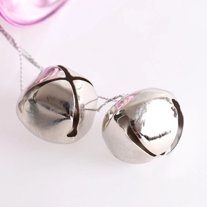 Pair of polished silver metal Christmas bells with hanging cords on white background