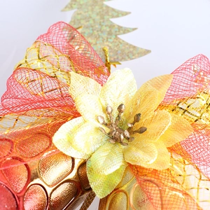 Detail of Christmas ornament featuring yellow floral motif and festive gold mesh ribbon