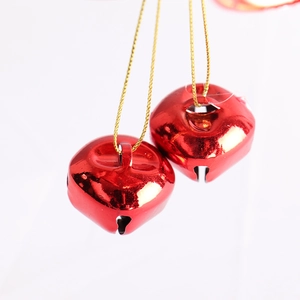 Close-up of red heart-shaped Christmas bells with shiny finish and golden string hangers