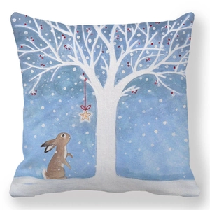 Detail of bunny looking at white tree with red berries on blue pillow cover