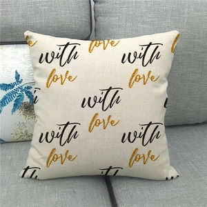 Close-up of linen pillowcase with with love gold glitter print on a gray fabric sofa