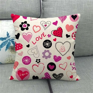 Detail of linen pillowcase with LOVE heart floral pattern on a gray fabric sofa