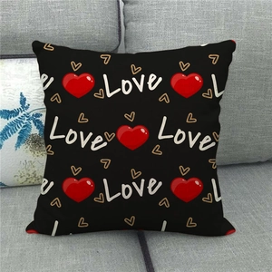Close-up of black linen pillowcase with Love script and red heart on a sofa