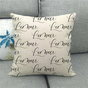 Close-up of linen cushion cover featuring black cursive L'amour print on grey sofa
