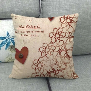 Close-up of linen cushion cover with husband text and heart button on gray sofa
