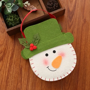 Detail van vilten sneeuwpop cadeauzakje met groene hoed op een rustieke houten achtergrond