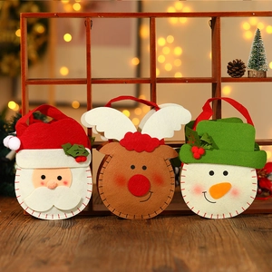 Drie vilten kerstcadeauzakjes met kerstman, rendier en sneeuwpop op een houten tafel
