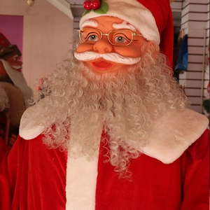Close-up of lifelike Santa Claus face with gold glasses and curly white beard detail
