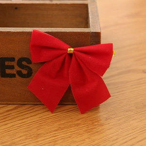 Detailed view of red velvet Christmas bows with gold metallic ties on a rustic wooden table