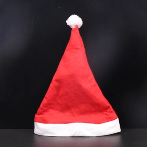 Close-up of a classic red Santa hat with white plush trim and pompom on black background