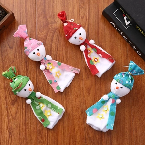 Detail of four colorful snowman gift bags with 3D carrot noses on wooden floor decor