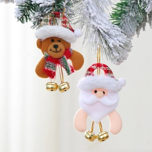 Plush Christmas bear and Santa ornaments with gold bells hanging on a snow-covered tree