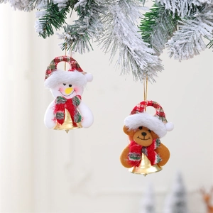 Plush Christmas snowman and bear ornaments with bells hanging on a snowy pine tree