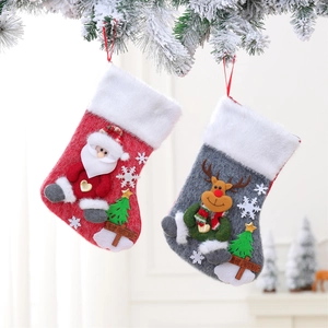 Large Christmas stockings with Santa and reindeer hanging on snow-covered branches