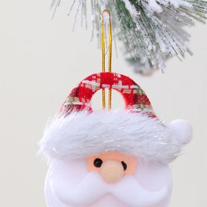 Macro shot of fabric Santa Claus ornament with bells hanging on snowy Christmas tree