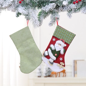 Set of red and green Christmas stockings with wooden plaques hanging on snowy pine branches