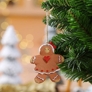 Girl gingerbread man ornament with red bow and heart hanging on a festive Christmas tree branch