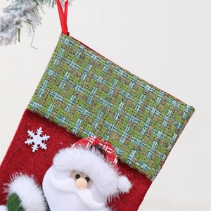 Detail of red burlap Christmas stocking with plush Santa doll and snowflake applique