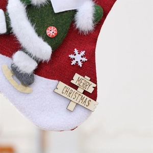 Detailed view of red burlap Christmas stocking with plush Santa and wooden Merry Christmas tag