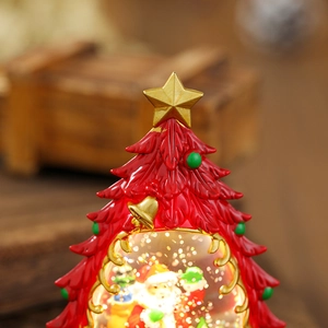 Detail of red Christmas tree lantern with golden star and Santa Claus snow globe