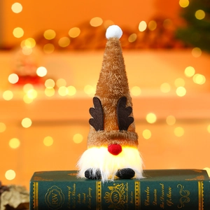 Close-up of glowing Christmas gnome ornament with reindeer antlers on a green book