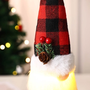 Macro shot of lighted Christmas gnome hat with red plaid, pine cones and berries