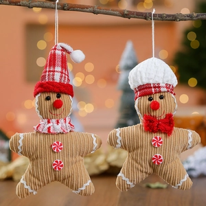 Christmas gingerbread man plush ornaments with red scarves hanging on a festive tree branch