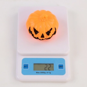 Vue détaillée d'une lanterne citrouille LED d'Halloween pesant 22g sur une balance