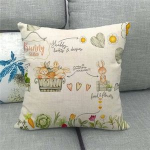 Close-up of linen Easter pillow cover with bunny and carrot print on a gray sofa