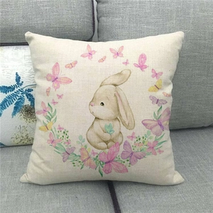 Detail of linen pillowcase with watercolor bunny and butterfly wreath on a grey sofa