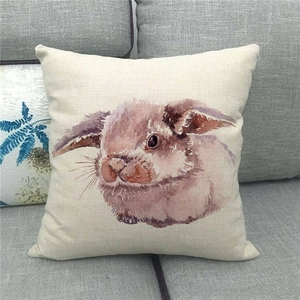 Close-up of a rustic linen cushion featuring a watercolor Easter bunny on a sofa