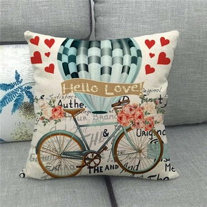 Detail of linen pillowcase with retro bicycle and hot air balloon on a grey sofa