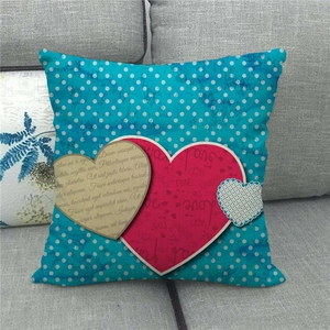 Teal polka dot linen pillow case with red heart love design on a grey sofa