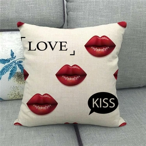 Detail of linen pillowcase with red lips and Love Kiss text on a gray sofa cushion