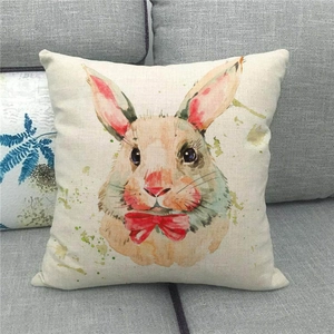 Detail of square linen pillowcase with watercolor bunny and red bow on a gray sofa