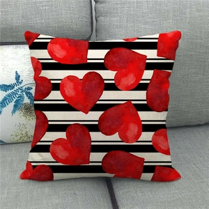Close-up of linen pillowcase with black stripes and red hearts on a grey sofa