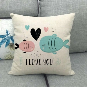 Dettaglio federa in lino con scritta I LOVE YOU e pesci su un divano grigio moderno